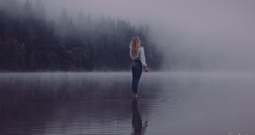 Woman walking through mist and water